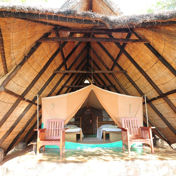 Each of the smaller tents are located under a vast thatched roof...