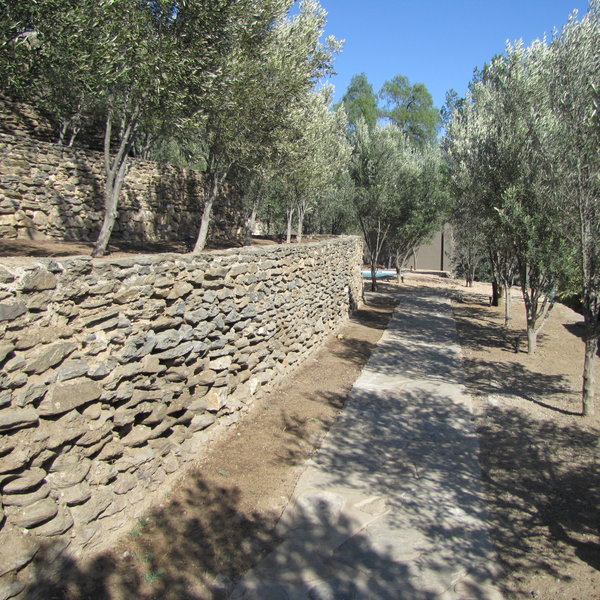 Cobbled walkways lead through terraced gardens dotted with olive trees and fountains...