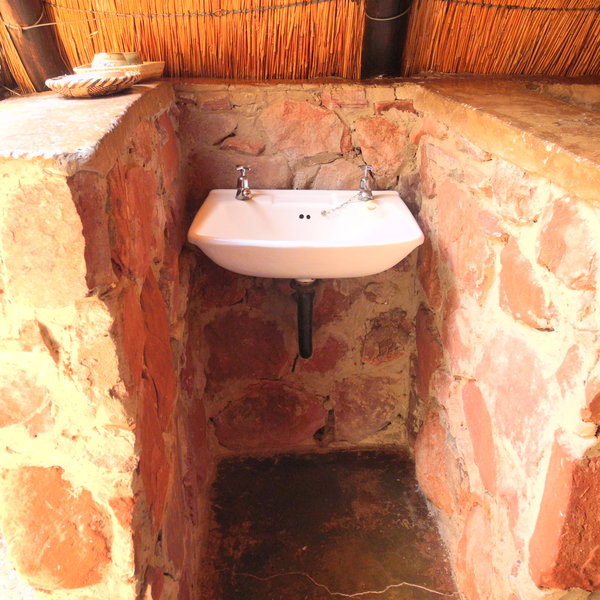 ... and a bathroom with a basin and toilet separated by a low wall ..