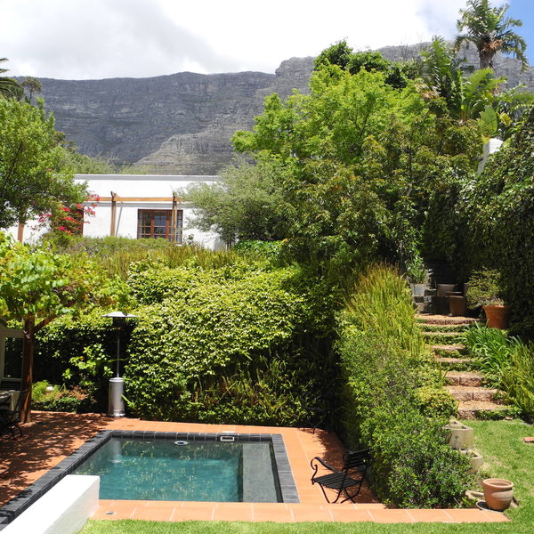 with a small pool and stairs leading to the cottage behind.