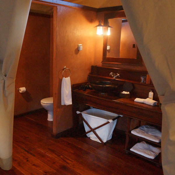 The en-suite bathroom includes double basins which are set into a wooden shelf, beneath twin mirrors