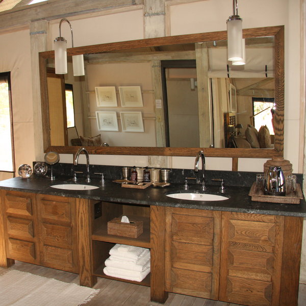 The en-suite bathroom includes twin basins set in a black marble unit beneath a large mirror…