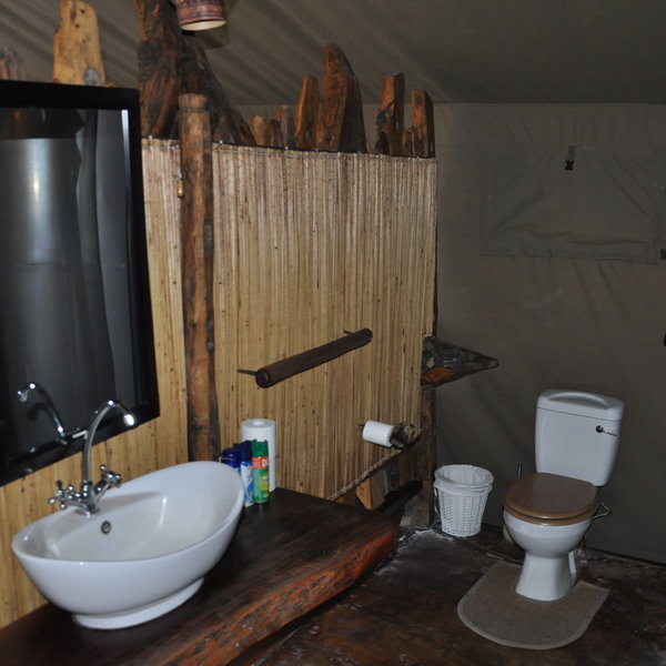 The bathrooms are set behind a wooden and cane screen with a toilet, a sink...